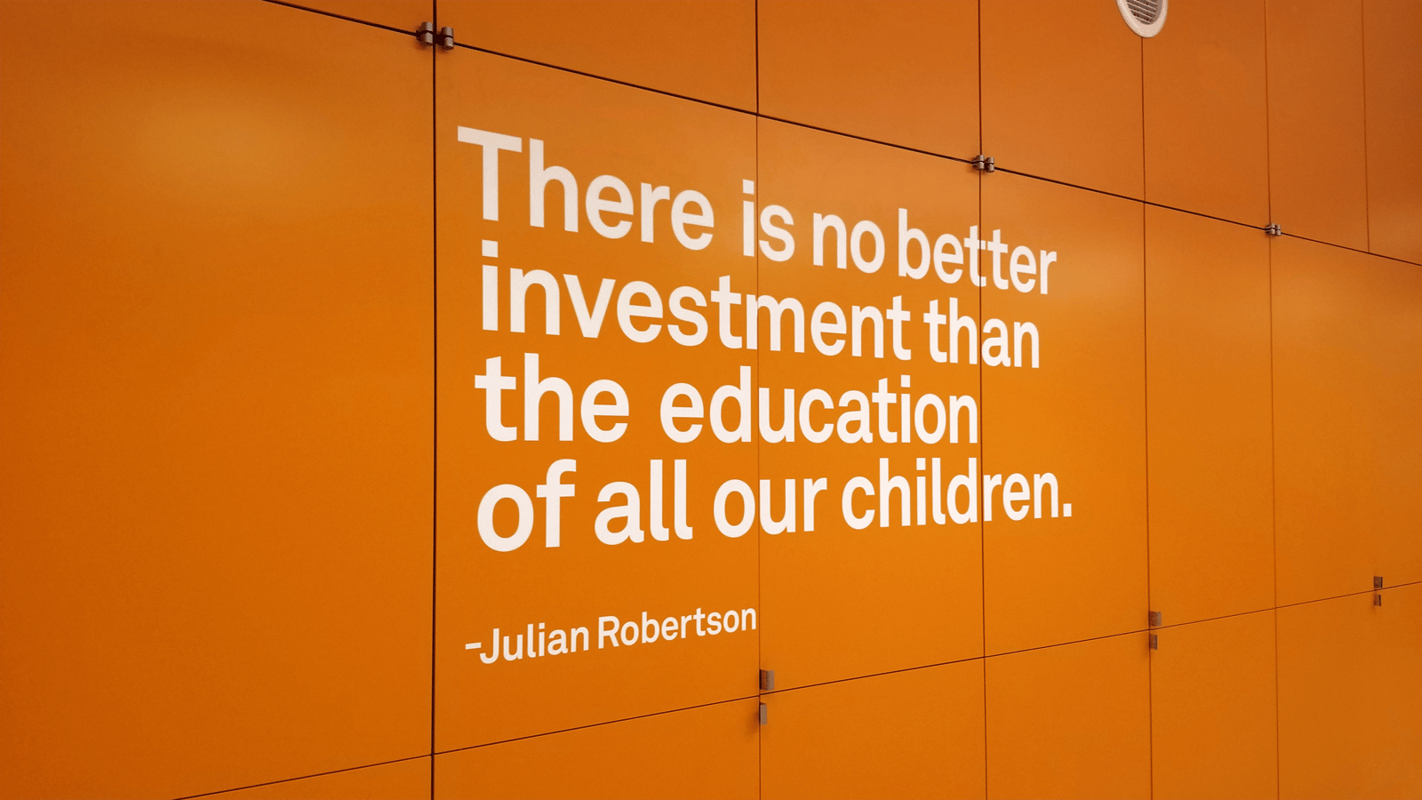 Large-scale interior wall typography carrying a quotation across an orange corridor wall