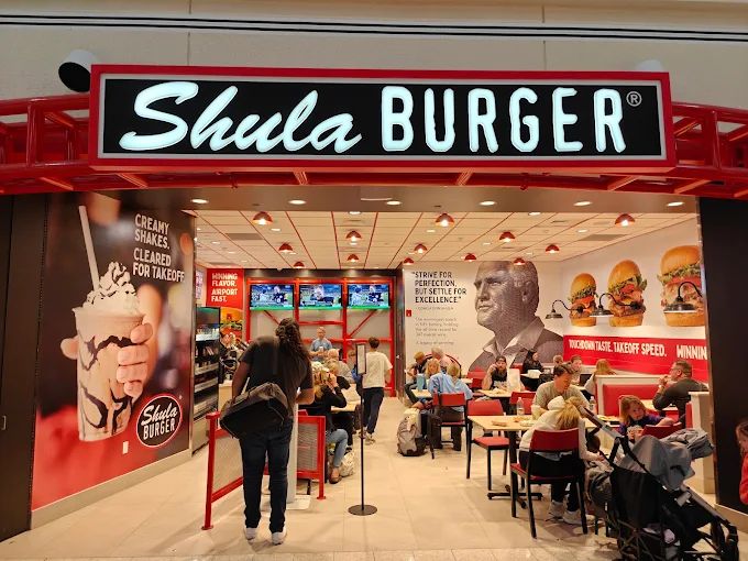 Illuminated Shula Burger cabinet sign above the entrance to a branded restaurant interior.