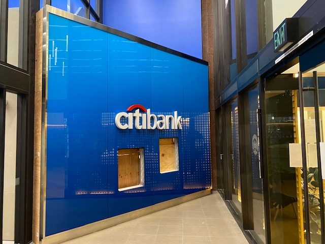 Interior bank reception wall with a large blue backlit glass panel and illuminated brand logo