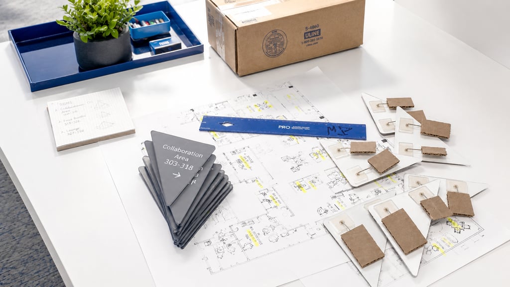 Signage planning materials, floor plans, and wayfinding samples arranged on a workspace for review
