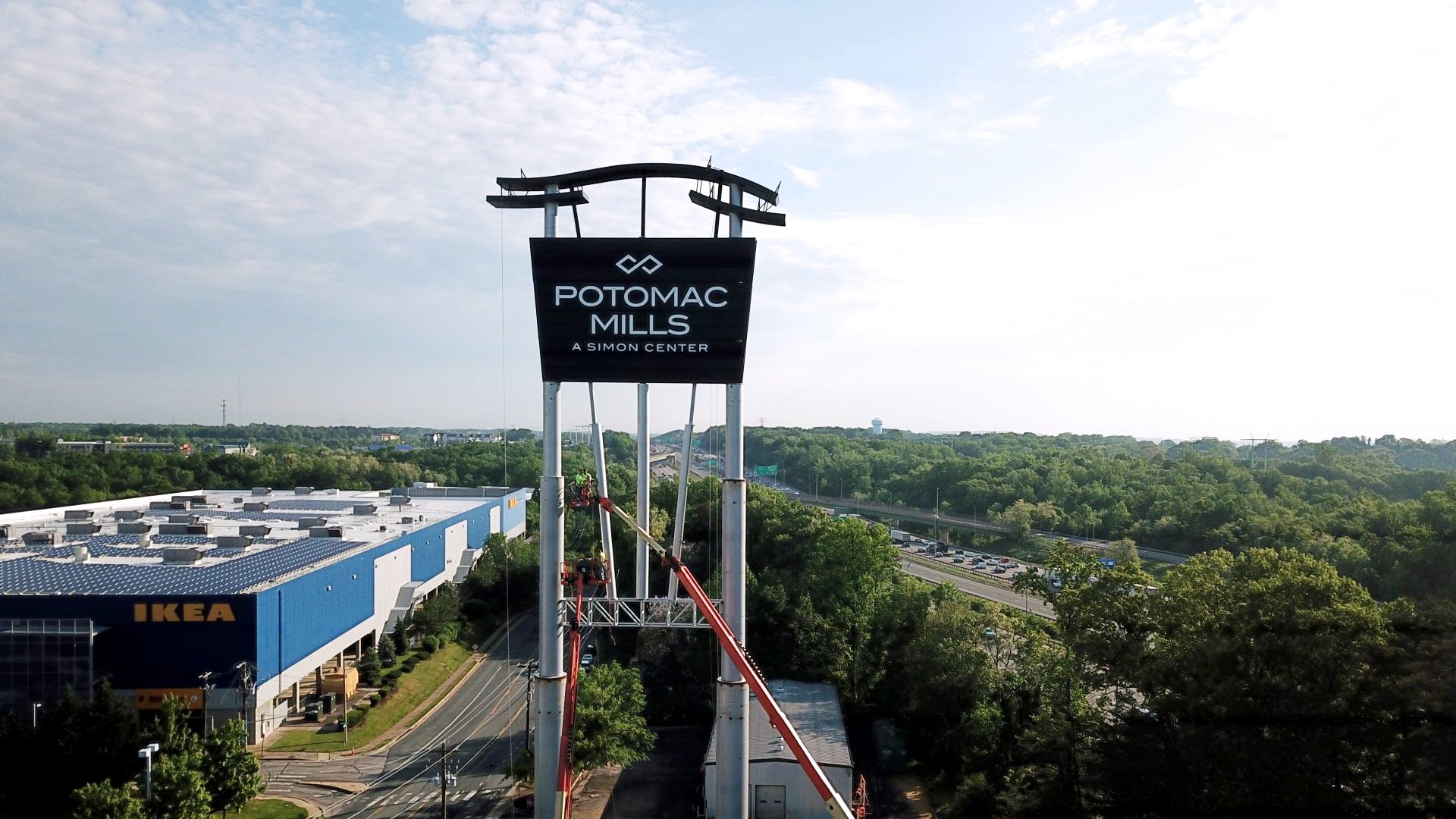 Daylight aerial view of the complete Potomac Mills pylon sign above the surrounding retail site and highway.