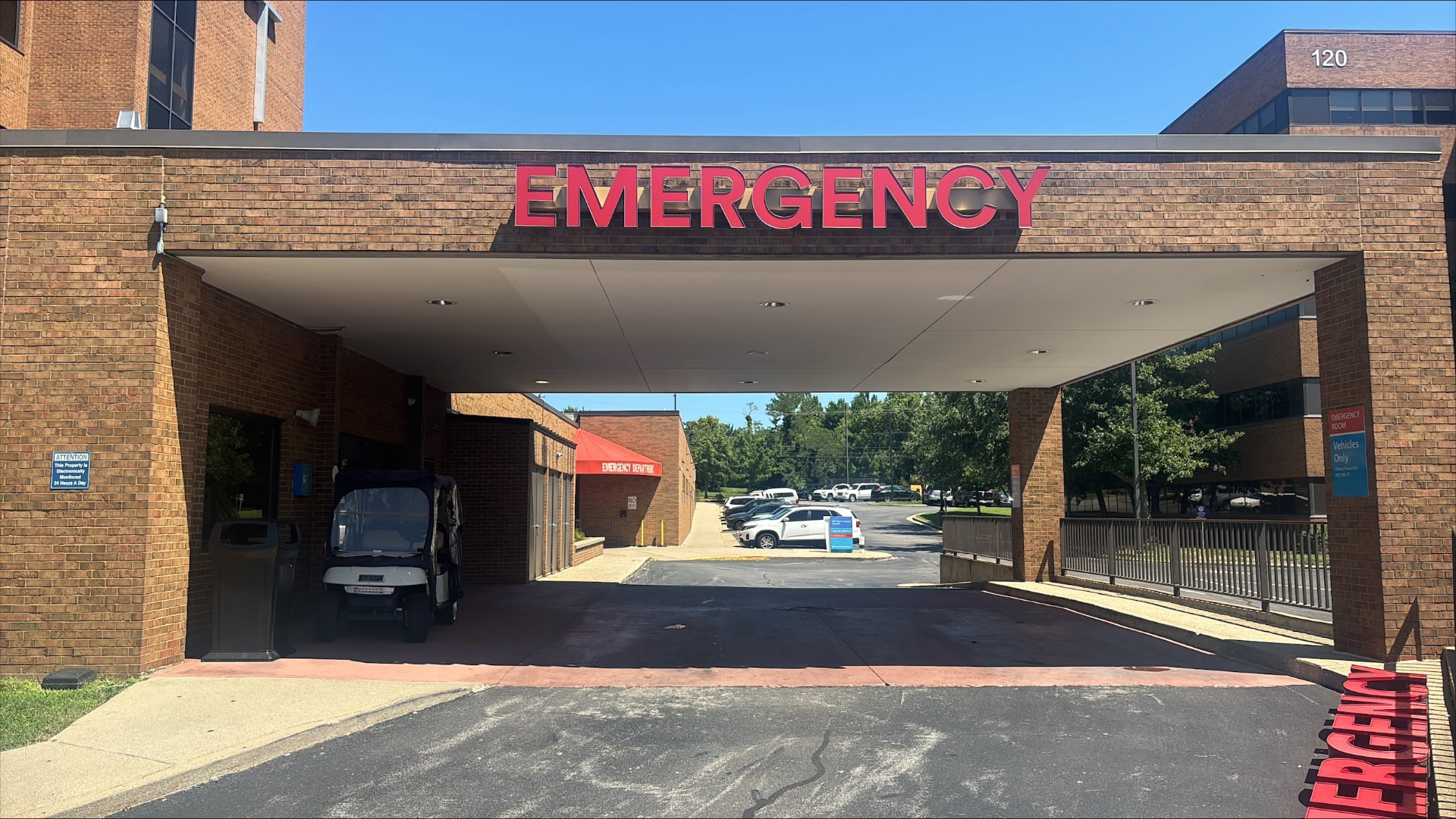 Red EMERGENCY channel letters mounted on a brick hospital entrance canopy in daylight