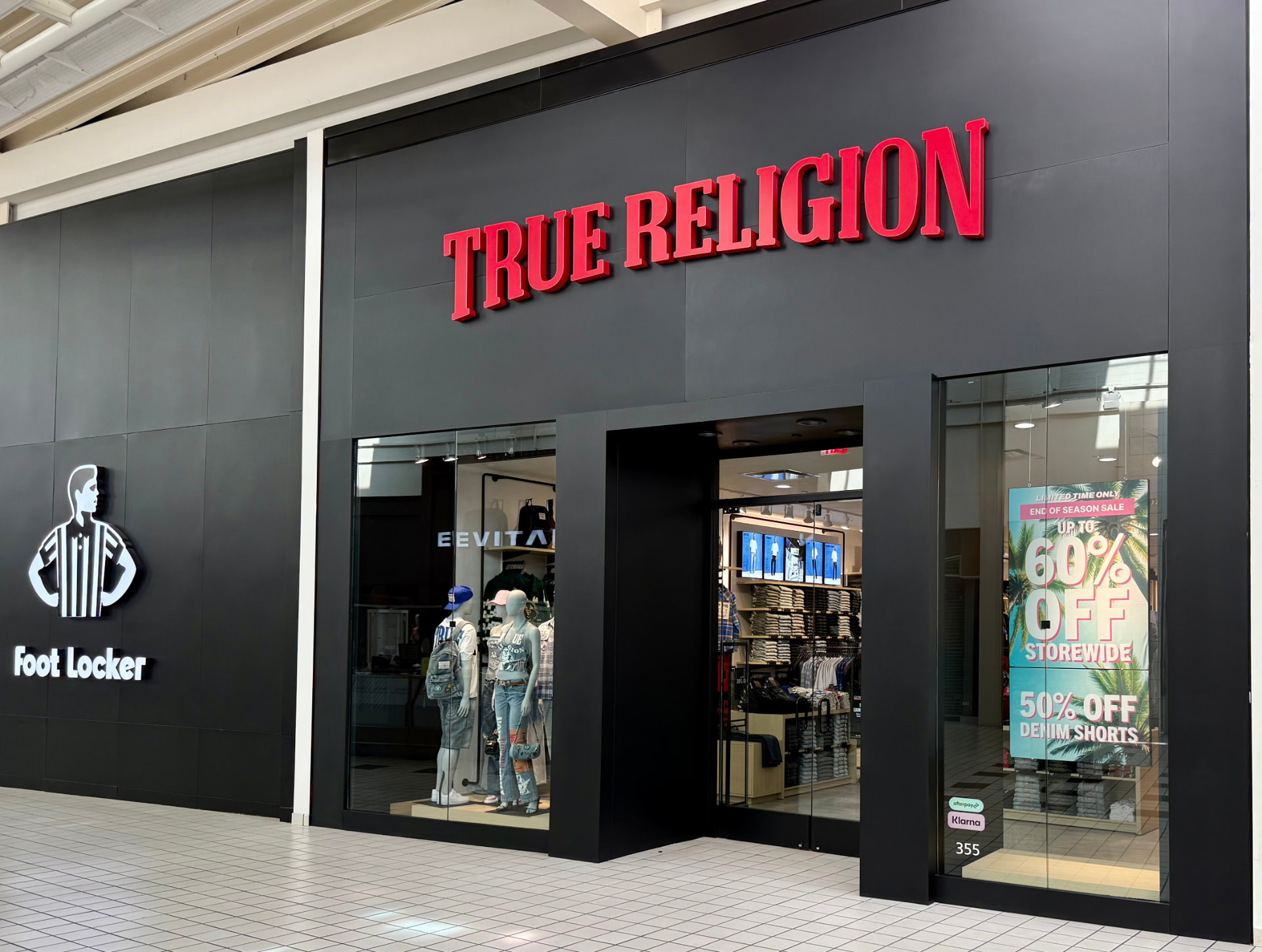 Illuminated True Religion retail storefront signage at a shopping mall