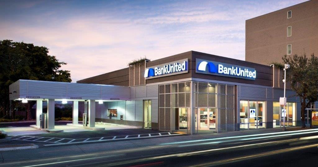 BankUnited branch at dusk with illuminated fascia signage and drive-thru canopy