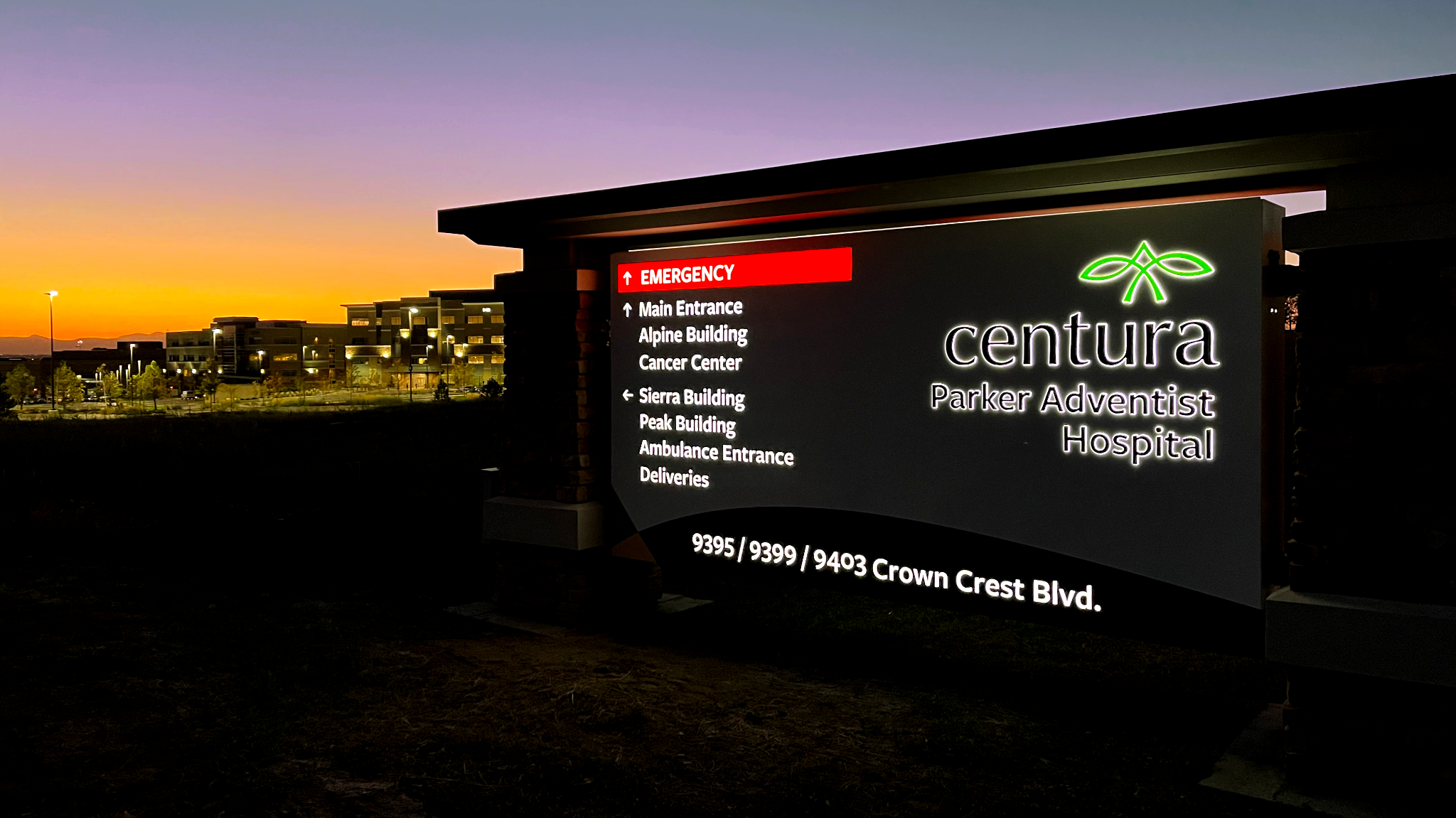 Illuminated hospital identification and wayfinding signage at dusk