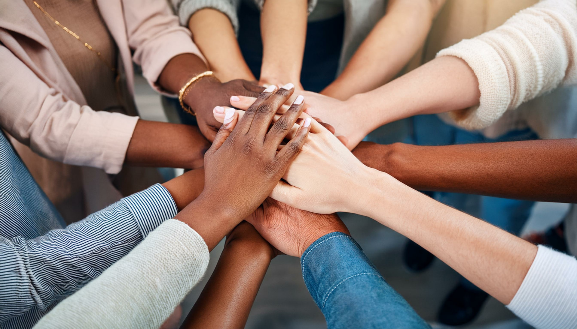 Diverse team members joining hands together in unity and collaboration.