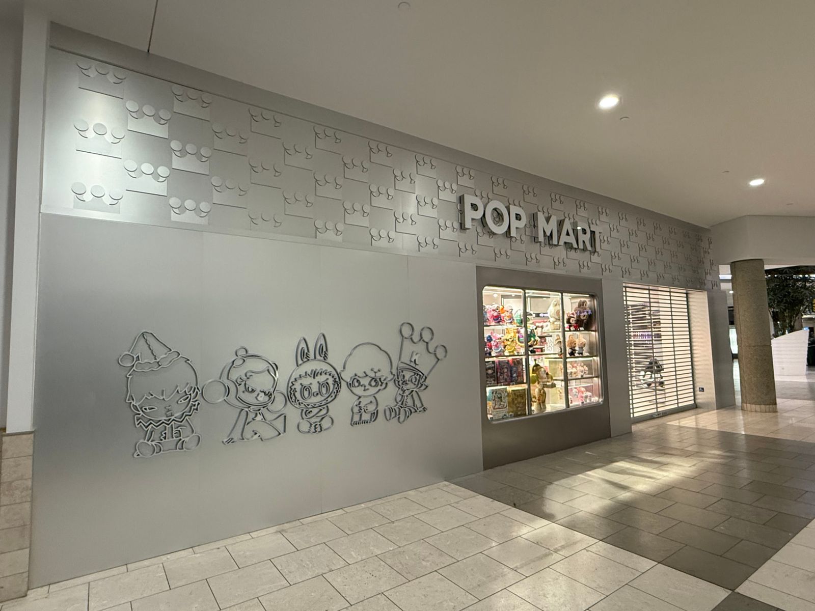 Pop Mart retail storefront with dimensional crown logo wall and character graphics