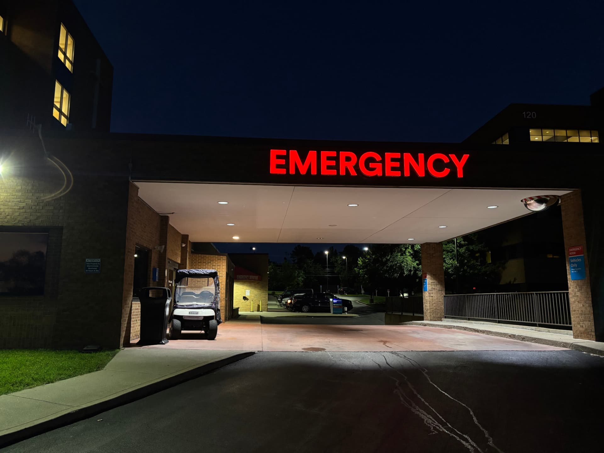 Red illuminated EMERGENCY channel letters glowing above a hospital entrance canopy at night